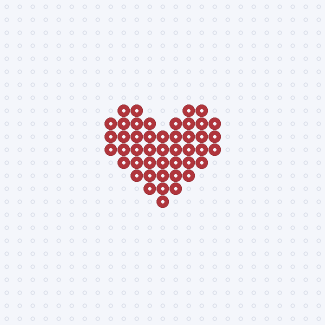 A small red heart shape as a fuse-bead pattern on a pegboard grid.